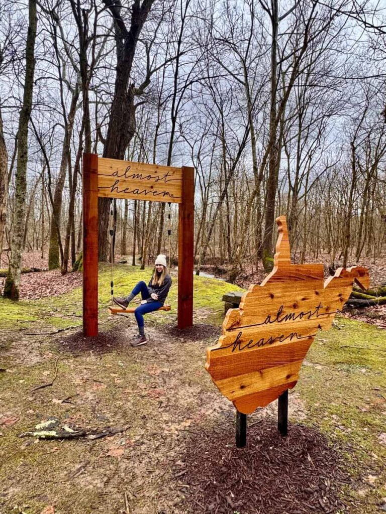 A woman sits on an "Almost Heaven" swing in a West Virginia forest