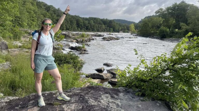 A woman stands on a rock with the Youghiogheny River in the background