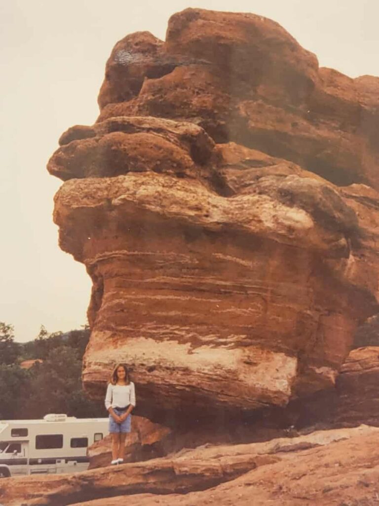 A girl stands in front of Balanced Rock at Garden of the Gods in Colorado
