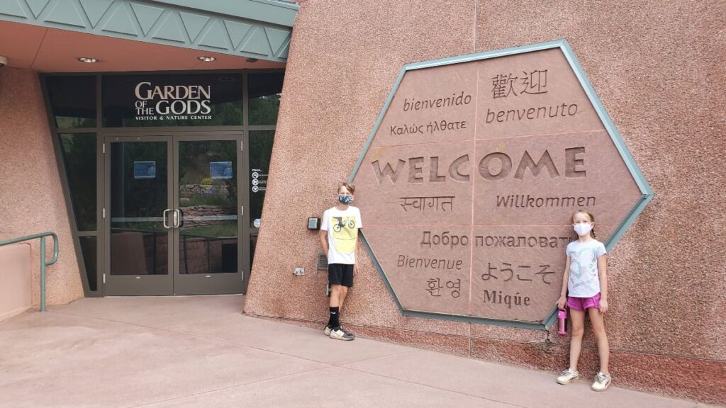 Two kids stand in front of the Visitor Center at Garden of the Gods