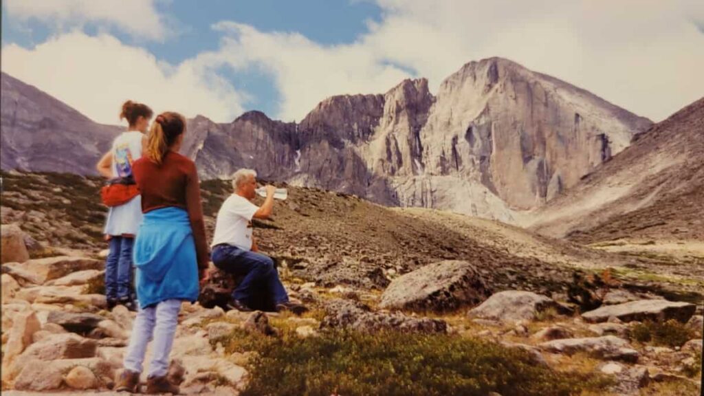 Two daughetrs wait as their father rests and takes a drink on a trail near Longs Peak in Colorado