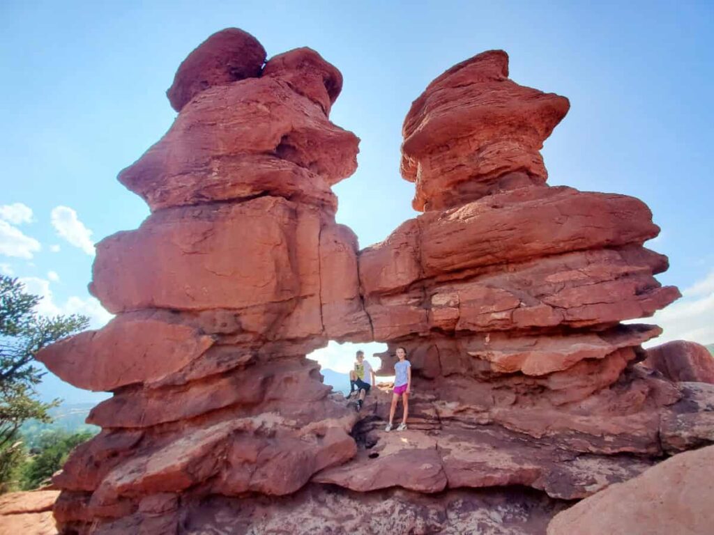 Two kids sit inside a rock formation called Siamese Twins