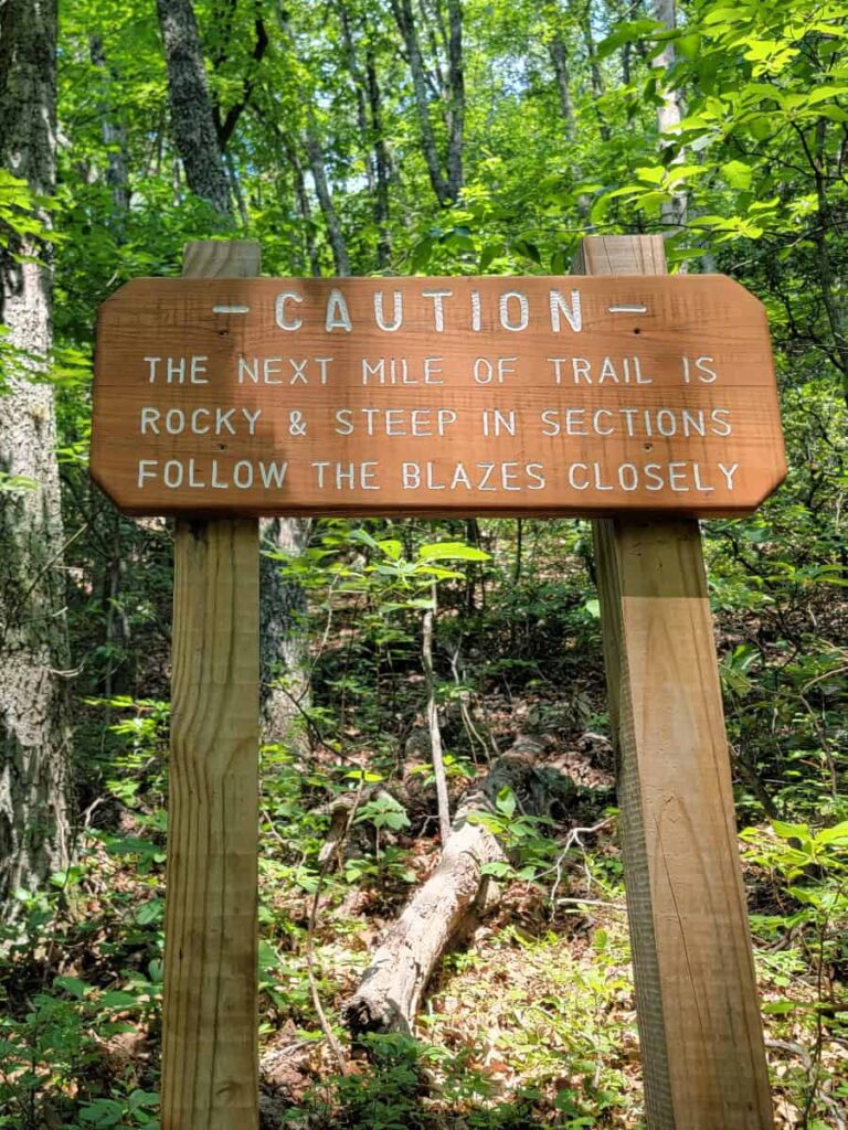 Caution sign notifies hikers of rocky and steep sections along the trail to Dragon's Tooth