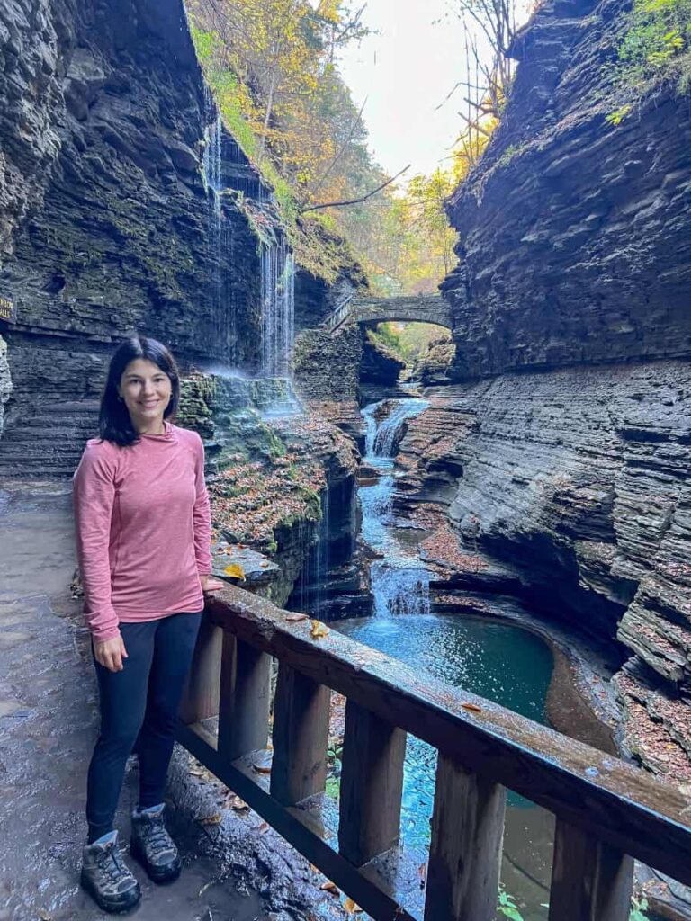 A woman stands at Watkins Glen in front of a waterfall