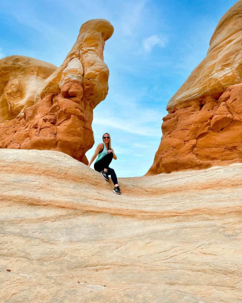A women sits below a red rock arch