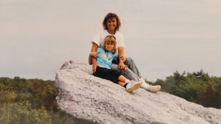A mother and young daughter sit on a rock outcropping