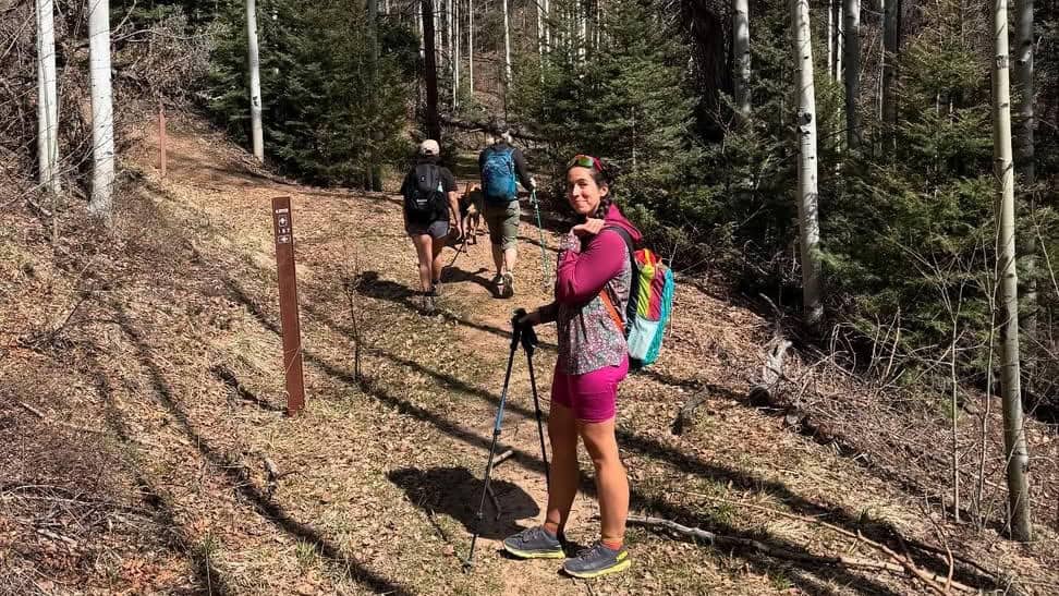 A woman looks back and smiles on a hiking trail