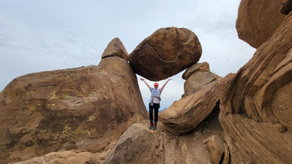 A woman stands in a hole formed by multiple boulder