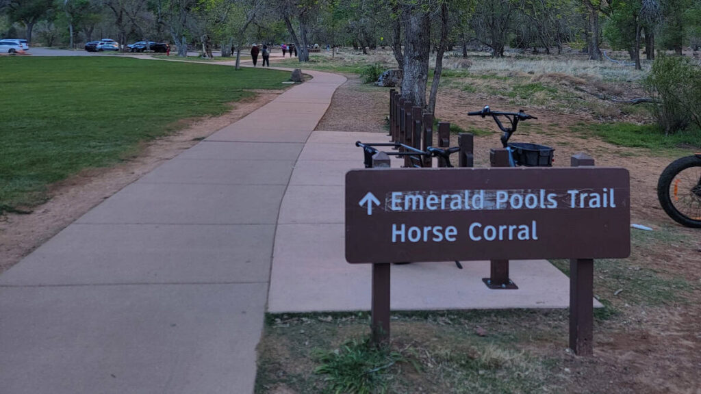 A sign points the direction to the Emerald Pools Trail from Zion Lodge