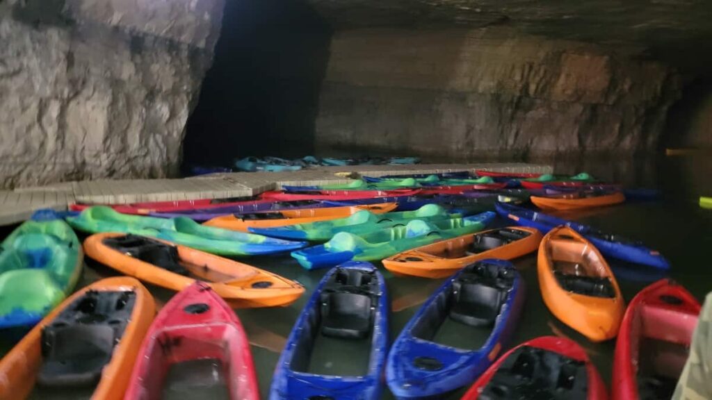 Kayaks float in the water inside the cave waiting for boaters to get in