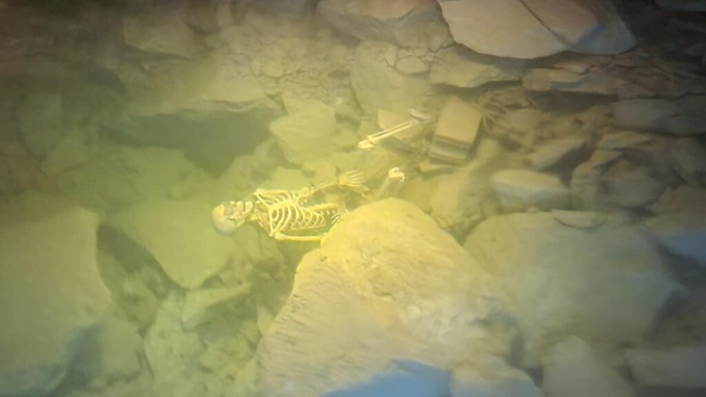 a fake skeleton sits on the bottom of the mine floor under water